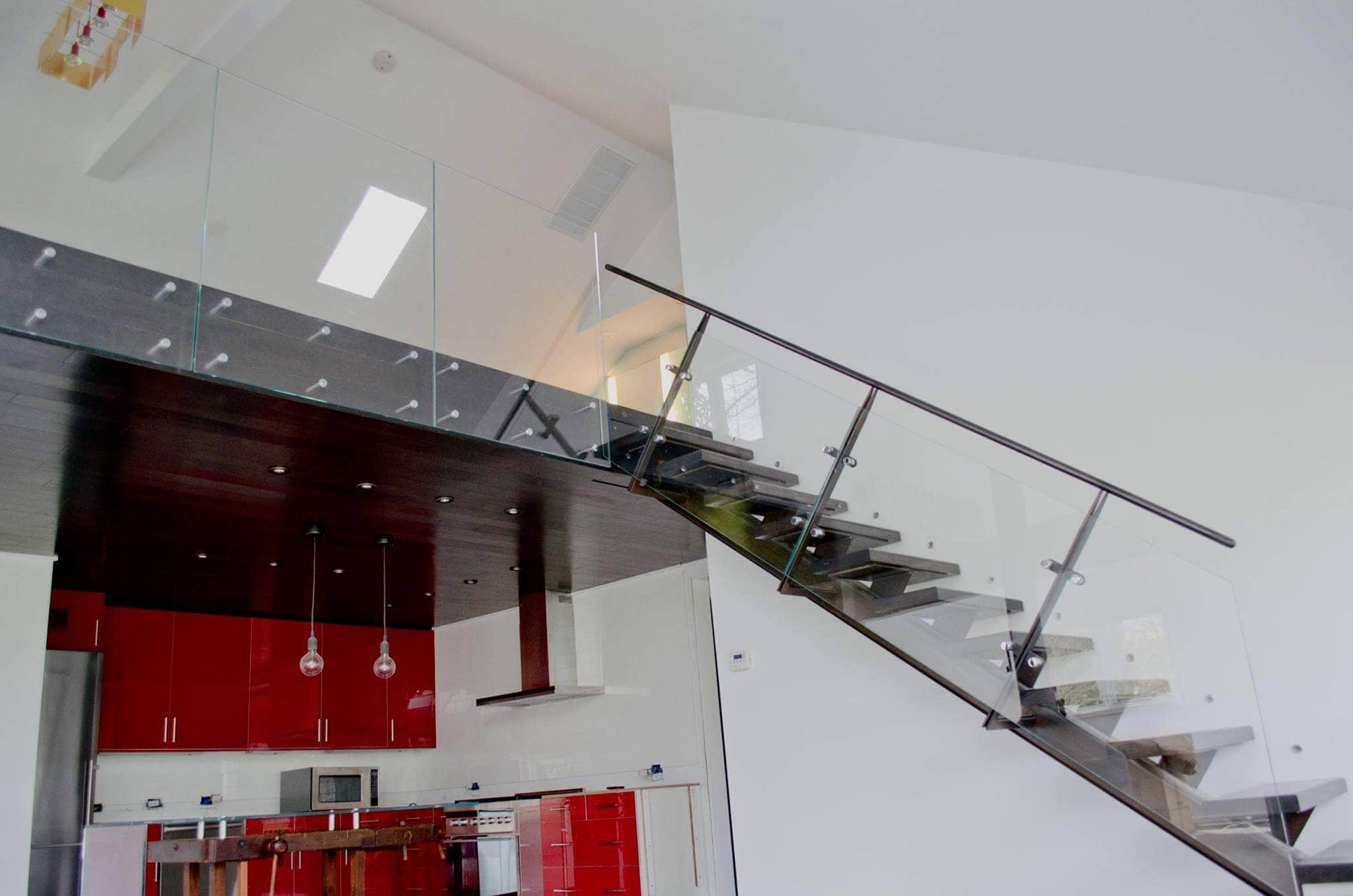 Modern glass staircase with black steps and sleek glass railing – stylish home interior. Elegant glass staircase with black steps and clear glass railing in contemporary home design.