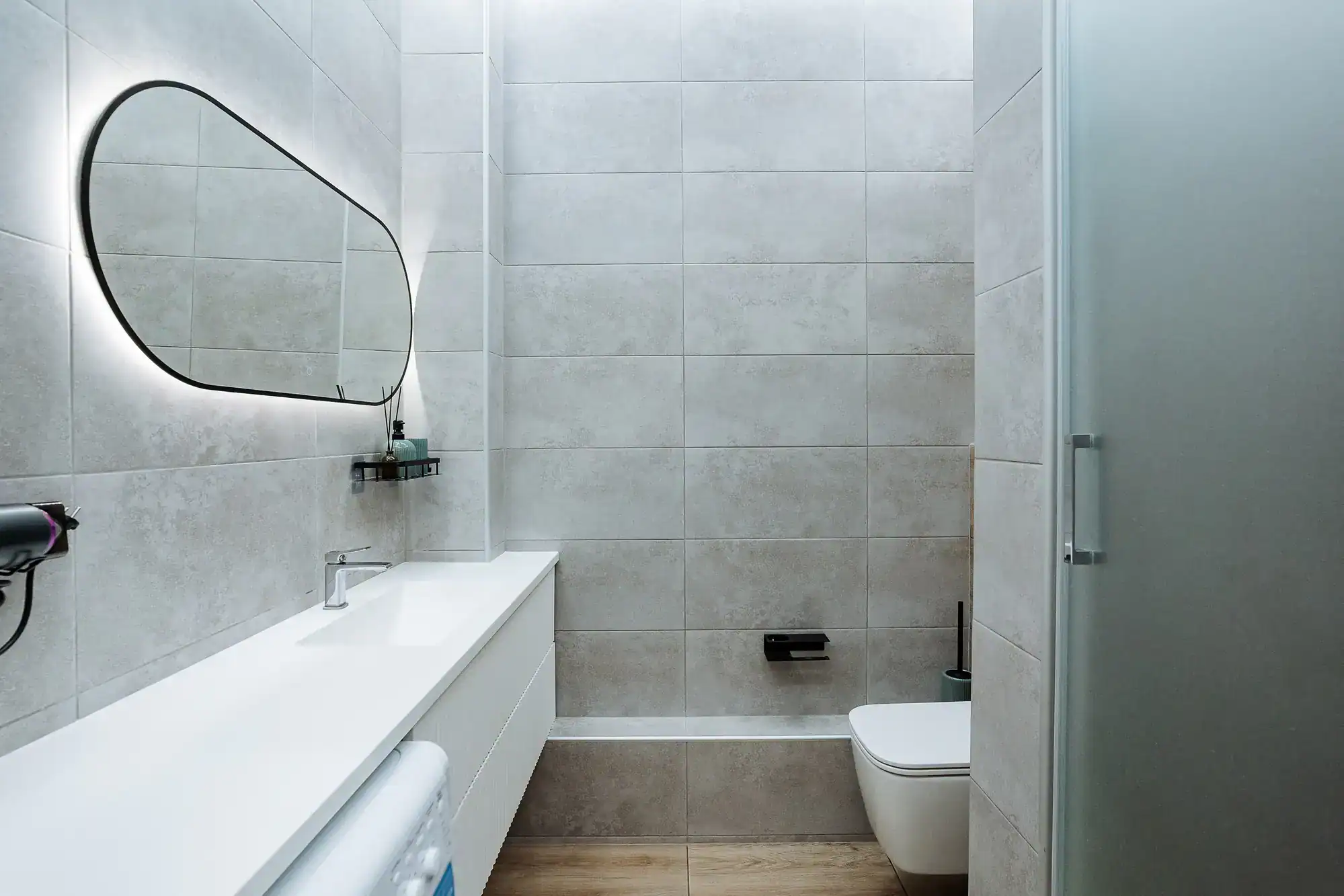 Bathroom with elegant glass shower enclosure, wall-mounted sink, and contemporary fixtures.