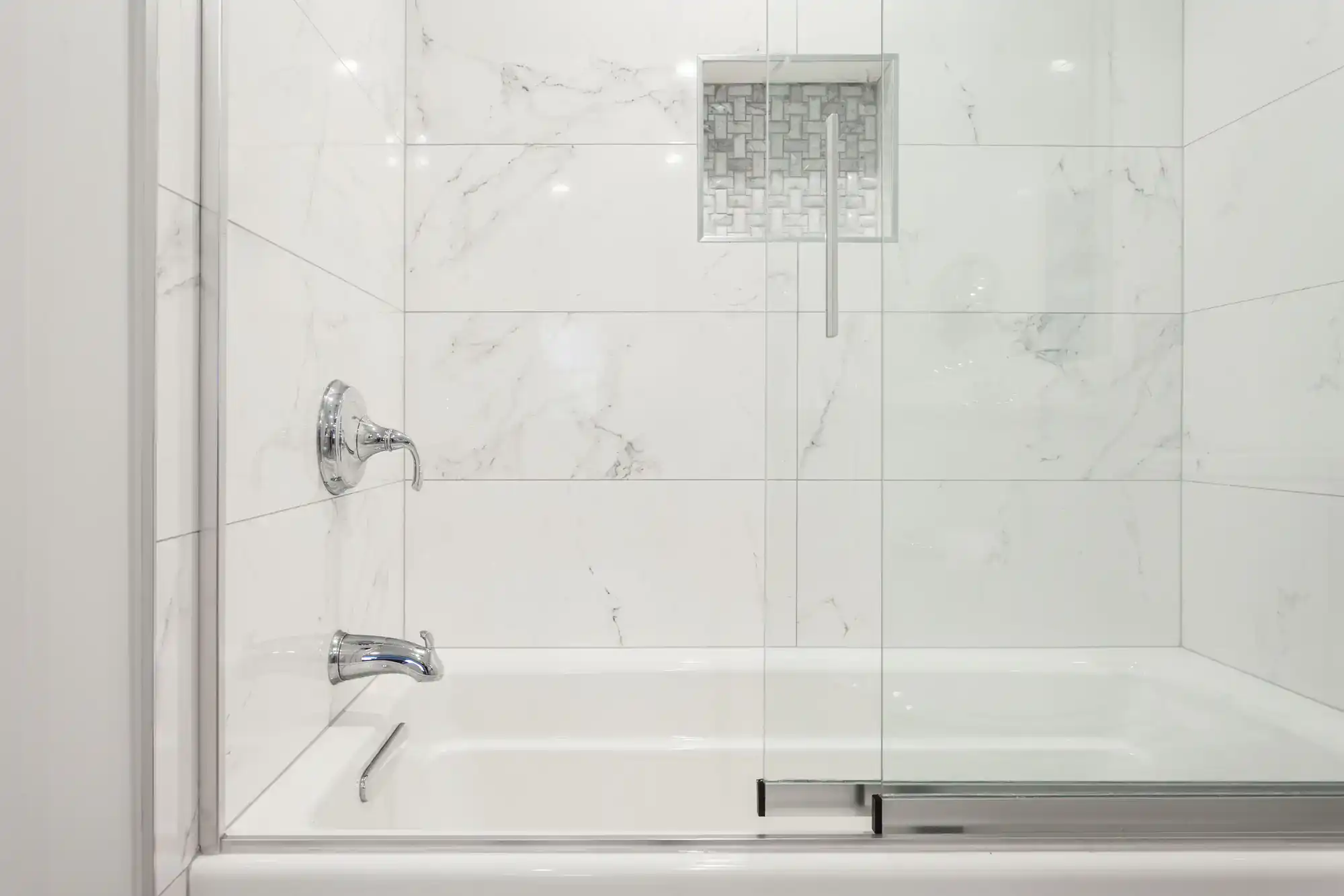 High-quality glass shower door with chrome handle and marble tile walls for modern bathrooms.