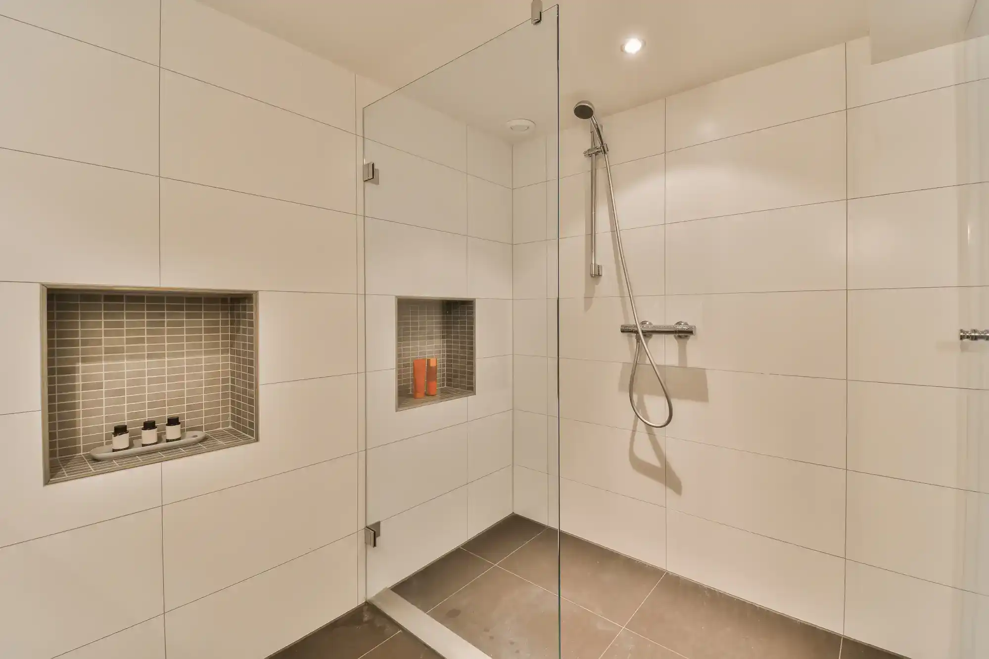 Glass shower enclosure with clear panels and chrome hardware for a minimalist look.